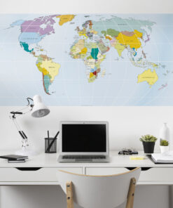 Modern white desk workspace with a laptop, monitor, task lamp, and small potted plants in front of a large world map wall poster