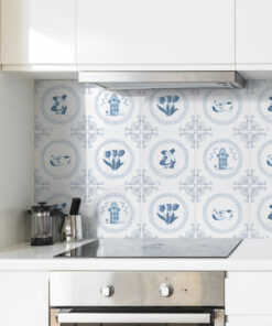 White kitchen with stainless steel oven and stovetop beneath decorative blue Delftware tiles on the backsplash.