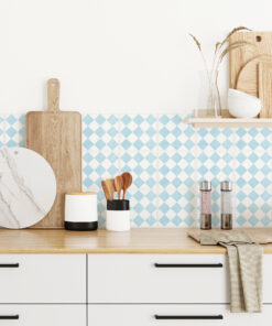 Kitchen counter with wooden cutting boards, marble round board, utensils, and salt/pepper grinders against blue diamond tile backsplash with white drawers below