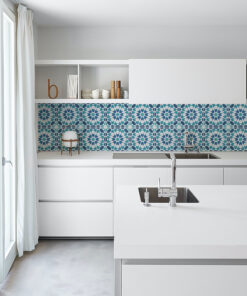 Minimalist white kitchen with a teal-blue geometric tile backsplash, open shelves, and a stainless sink.