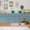 | Casadart | Vinis Autocolantes, Papel de Parede e Painéis Decorativos White kitchen counter scene with glass jars, teal cups, and a faucet set against a blue geometric tile wall with framed art above.