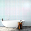 03 copy | Casadart | Vinis Autocolantes, Papel de Parede e Painéis Decorativos White freestanding bathtub in a bathroom with blue-and-white diamond tile walls; a wooden stump stool holds bath products.