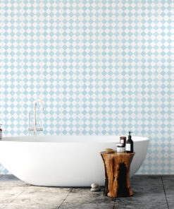 White freestanding bathtub in a bathroom with blue-and-white diamond tile walls; a wooden stump stool holds bath products.