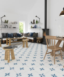 Bright open living room with white walls, blue star-pattern tiled floor, and wooden stools around a coffee table and dining table area near a wood stove.