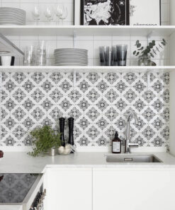 White kitchen with patterned tile backsplash, open shelves holding plates, glasses, and herbs near the sink.