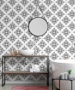 Modern bathroom with black-and-white geometric tiled wall, round wall mirror, and white vessel sink on a metal frame with pink rug below.
