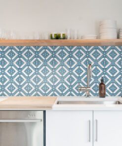 Kitchen shelf with glassware, mugs, and white plates above a geometric blue tile backsplash near a sink and faucet.