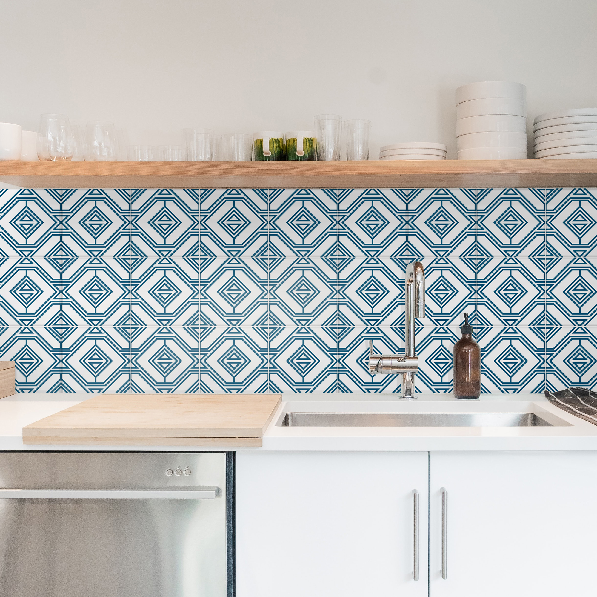| Casadart | Vinis Autocolantes, Papel de Parede e Painéis Decorativos Kitchen shelf with glassware, mugs, and white plates above a geometric blue tile backsplash near a sink and faucet.