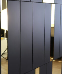 Dark gray panel wall with narrow vertical gold reflective strips, showing glimpses of the interior through the gaps.