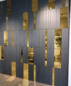 Facade of a modern building with blue vertical panels and gold-tinted windows, glimpses of a bright interior with seating and plants inside.