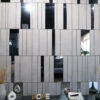 | Casadart | Vinis Autocolantes, Papel de Parede e Painéis Decorativos Modern interior showroom display: beige tiled wall with vertical black gaps, glass openings revealing decor like white vases, a plant, magazines, and the word 'HOME' on the shelf.