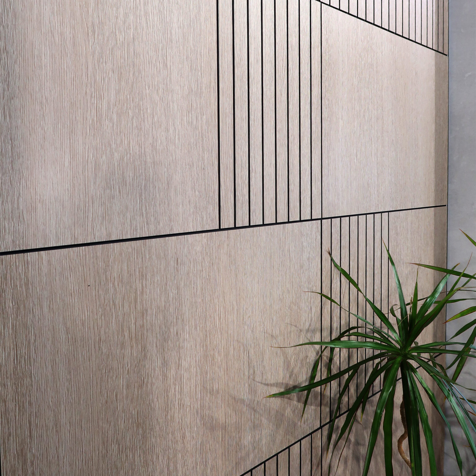 Beige wood-paneled wall with vertical black lines and a plant showing on the right side