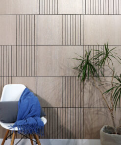 White molded chair with a blue fringed blanket, placed against a vertical wood-paneled wall; a tall plant in a pot on the right.