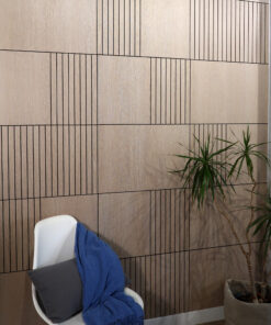 White plastic chair with a dark cushion and a blue blanket draped over it, set against a wood-paneled wall with vertical grooves; a potted plant appears on the right.