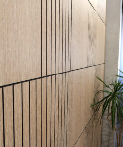 Wood-paneled wall with vertical black slats and visible grain, plant to the right edge.