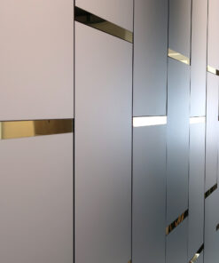 Abstract interior wall with vertical gray panels and narrow gold reflective slits creating a geometric pattern