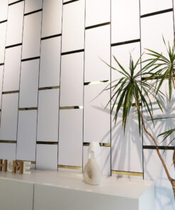 Modern interior with a white slatted wall, gold accents, and a white desk; two tall green plants appear on the right side.