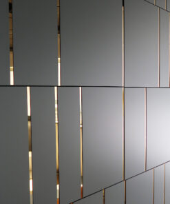 Vertical gray wall panels with slim gold-lined gaps letting warm light through.