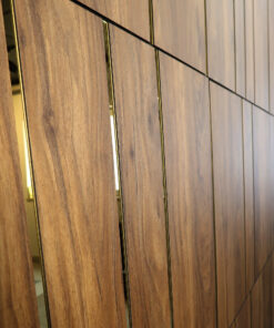 Close-up of a wood-paneled wall with vertical gold trim between panels and narrow dark gaps between sections.