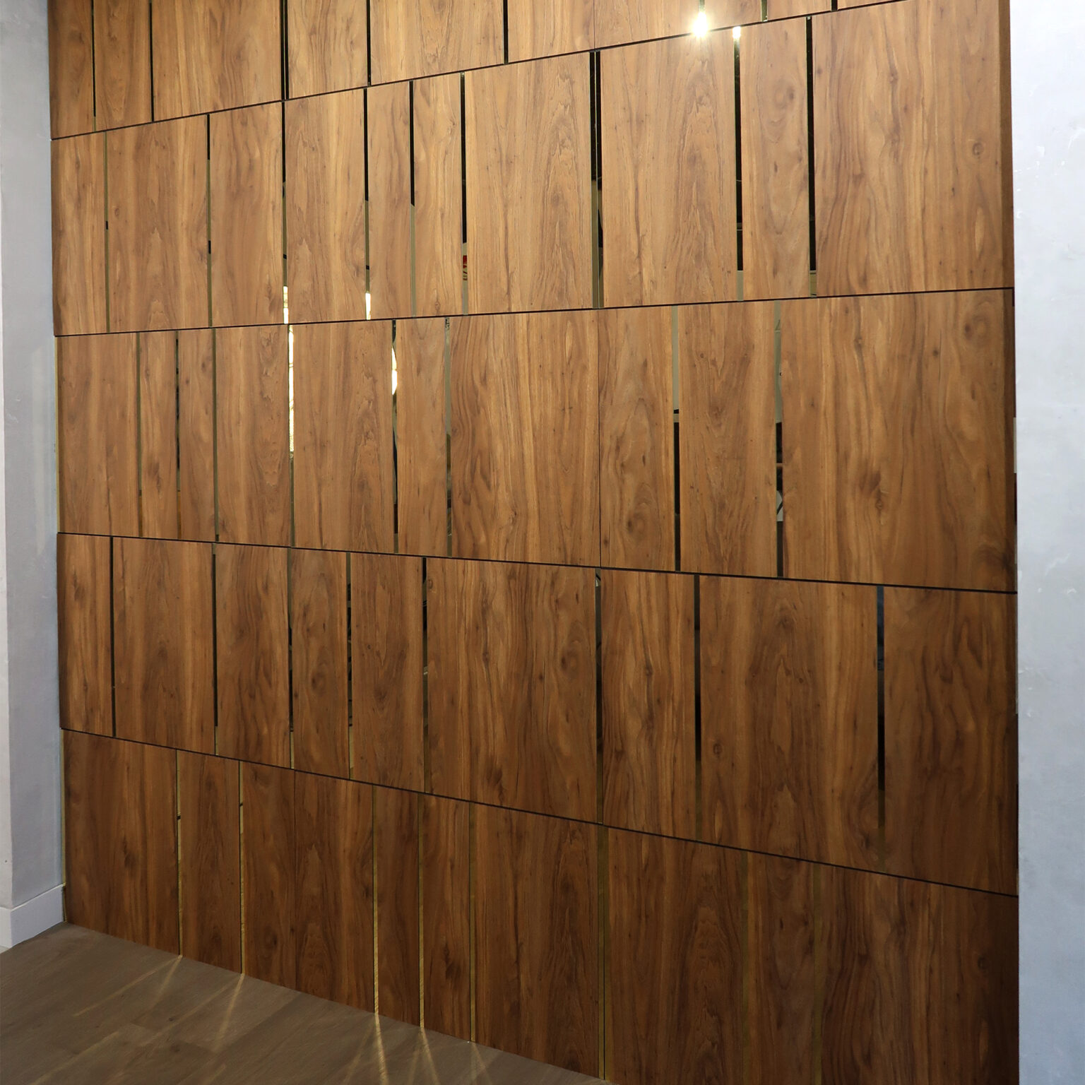 Wooden wall panels with vertical slats in a warm brown finish, corner of gray walls and light floor visible.