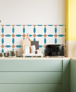 Pastel green kitchen counter with a patterned teal and brown tile backsplash, toaster, cutting board, and white jars.