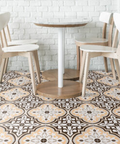 Round marble-topped table on a white pedestal, surrounded by light wooden chairs against a white brick wall.
