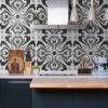 | Casadart | Vinis Autocolantes, Papel de Parede e Painéis Decorativos Modern kitchen with a stainless range hood, patterned gray tile backsplash, and countertop accessories (knife block, cutting boards, plant).