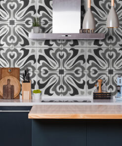 Modern kitchen with a stainless range hood, patterned gray tile backsplash, and countertop accessories (knife block, cutting boards, plant).