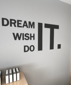 Wall features bold black typography reading 'DREAM IT WISH DO' with binders on a wooden desk below and a wooden slat divider on the right side of the image.