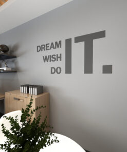 Office wall with large typography reading 'DREAM IT WISH DO IT' and a shelf displaying a lamp and files.