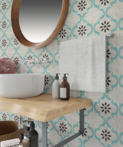 Bathroom vanity with a round wooden-framed mirror, curved white sink, and turquoise patterned wall tiles; bottles on a wooden shelf nearby.