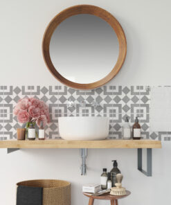 Round wooden-framed mirror above a marble sink with patterned tile backsplash and vanity items on a wooden counter.