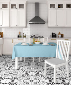 White kitchen with a stainless range hood, white cabinets, and a turquoise tablecloth-draped dining table.