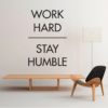 | Casadart | Vinis Autocolantes, Papel de Parede e Painéis Decorativos Minimalist room with a large wall quote: 'Work hard Stay humble', plus a wooden bench and a modern chair.