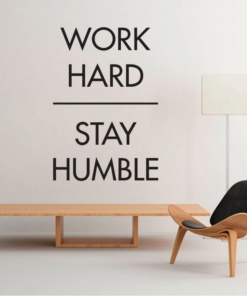 Minimalist room with a large wall quote: 'Work hard Stay humble', plus a wooden bench and a modern chair.