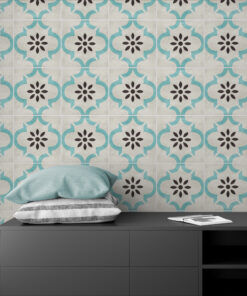 Patterned tile wall with teal interlocking shapes and black floral centers behind a dark gray dresser and blue cushions on top.