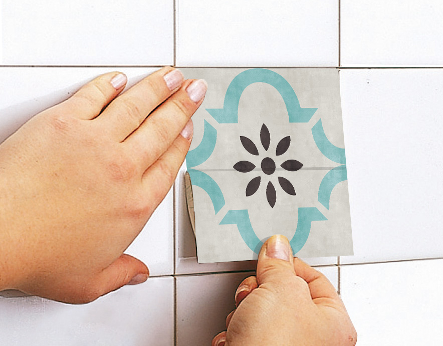 mao-azulejos | Casadart | Vinis Autocolantes, Papel de Parede e Painéis Decorativos Hands smoothing a decorative tile sticker onto a white tiled wall.