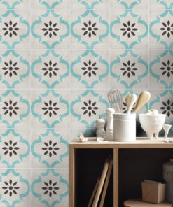 Decorative tiled backsplash with teal quatrefoil patterns and brown floral centers; a wooden counter with white canisters and kitchen utensils.
