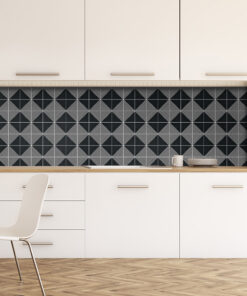 Minimalist kitchen with white cabinets, a light wood countertop, and a black-and-white geometric tile backsplash; a white chair on a herringbone floor.