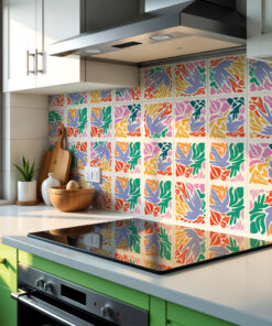 Modern kitchen with a stainless range hood, white countertops, and bright green drawers beneath a colorful patterned tile backsplash under natural light.