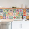 01 | Casadart | Vinis Autocolantes, Papel de Parede e Painéis Decorativos Colorful tiled backsplash above a white countertop with a stainless steel sink and faucet in a bright kitchen.
