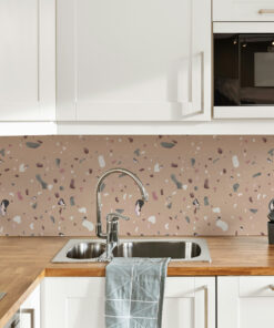 Modern white kitchen with a terrazzo pinkish backsplash, wooden counter, double sink and chrome faucet; blue-gray towel hangs over the sink.