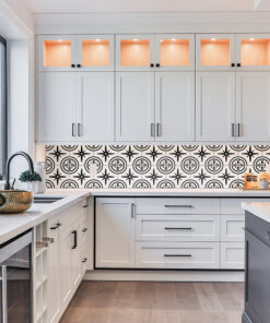 Bright white kitchen with shaker cabinets, black hardware, and a bold black-and-white patterned tile backsplash beneath upper cabinets.