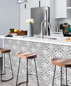 Modern kitchen island with three wooden stools, patterned tile front, and a sink with curved faucet on a white countertop.