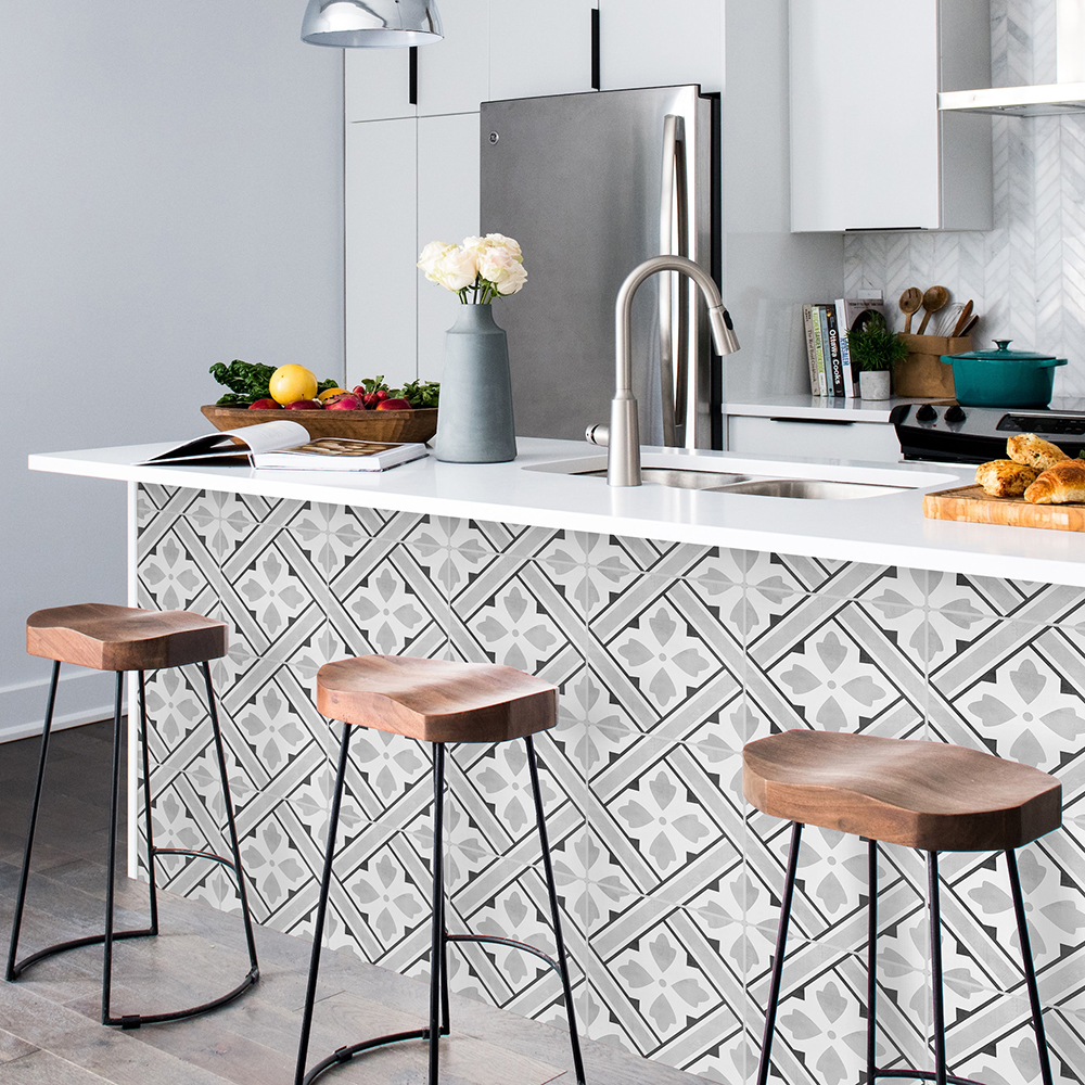 03 | Casadart | Vinis Autocolantes, Papel de Parede e Painéis Decorativos Modern kitchen island with three wooden stools, patterned tile front, and a sink with curved faucet on a white countertop.
