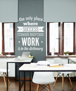 Office workspace with white chairs and laptops; a tall gray pillar displays the quote about success and work.