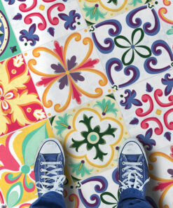 Top-down view of colorful ceramic tiles with intricate floral patterns; blue sneakers visible at the bottom edge.
