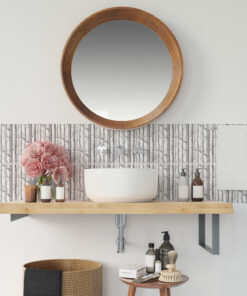 Round wooden-framed mirror above a white vessel sink with bottles and pink flowers on a wood counter.