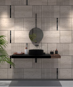Modern bathroom vanity with a round hanging mirror above a black vessel sink, geometric tiled wall, and a green plant on the left.