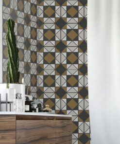 Tall cactus in a white pot sits on a wooden counter beside a bold geometric tile wall in gray, black, white and gold; white curtain on the right.